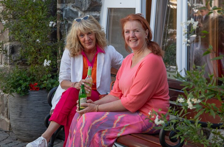 Zwei Frauen sitzen auf einer Bank auf dem Sommerfest im Hotel Deimann